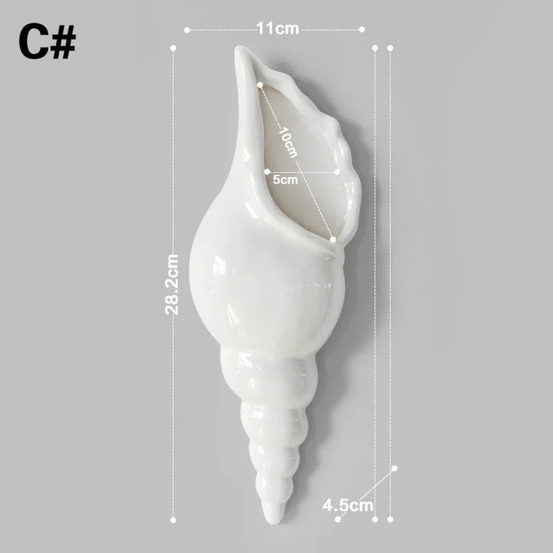 Overhead view of ceramic sea conch wall vase with white dried flowers
