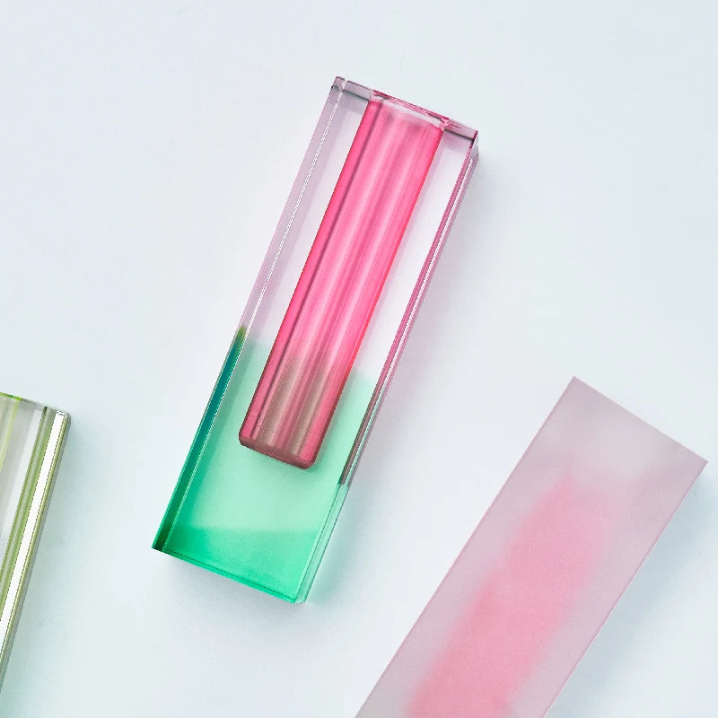 Short frosted pink-yellow acrylic pillar vase on a minimalist marble surface