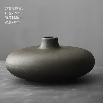 Abstract Japanese terracotta vase on concrete shelf with dried botanicals