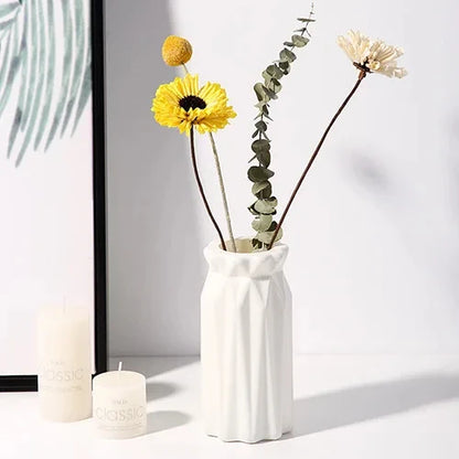 Top-down view of small white plastic Nordic vase on clean white surface