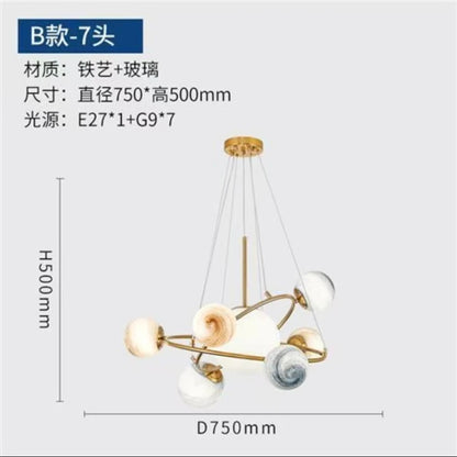 Globe chandelier lit in white light with gold plated metal arms