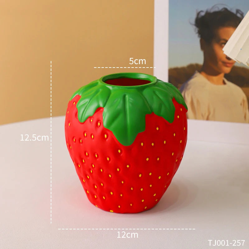 Pink strawberry vase with white daisy stems on a kawaii styled desk