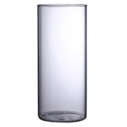 Small glass cylinder vase on bedroom nightstand holding single dried cotton flower