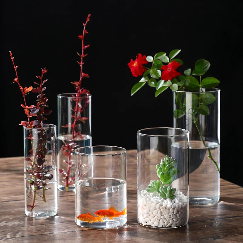 Clear glass cylinder vase on white table with fresh flowers
