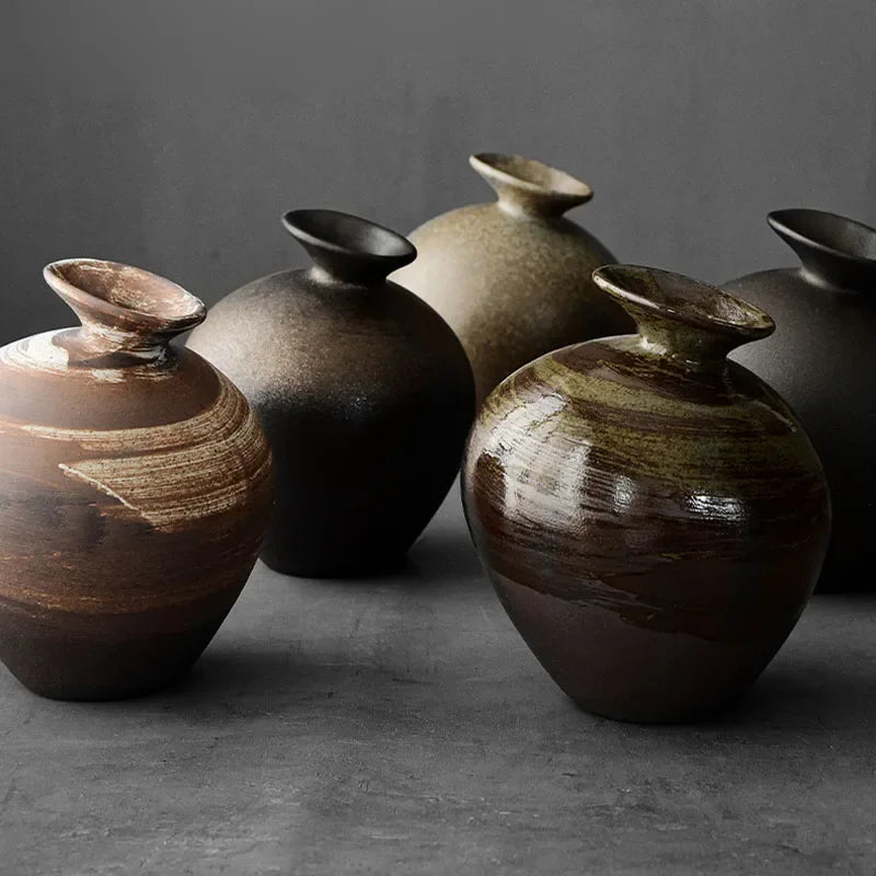 Five terracotta stone-look vases in different abstract shapes arranged together