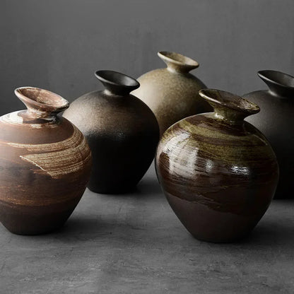 Five terracotta stone-look vases in different abstract shapes arranged together