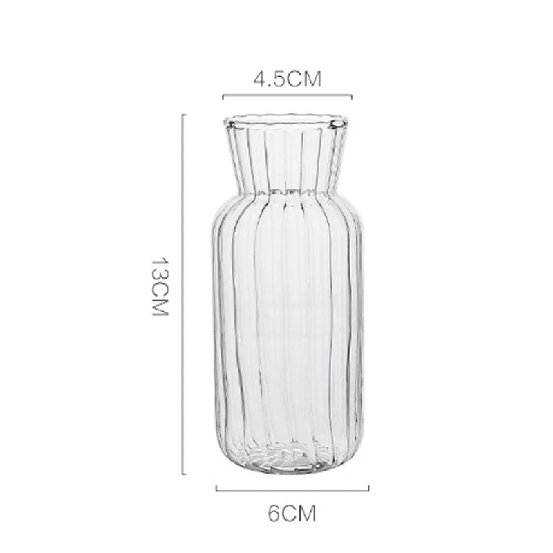 Nordic glass bottle vase holding fresh green stems on wooden dining shelf