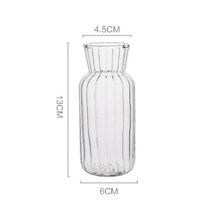 Nordic glass bottle vase holding fresh green stems on wooden dining shelf