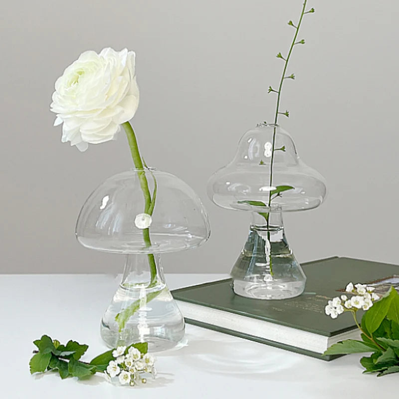 Mushroom shaped glass vase with plant stem on wooden shelf