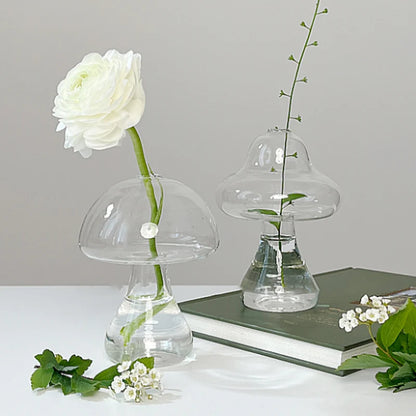 Mushroom shaped glass vase with plant stem on wooden shelf