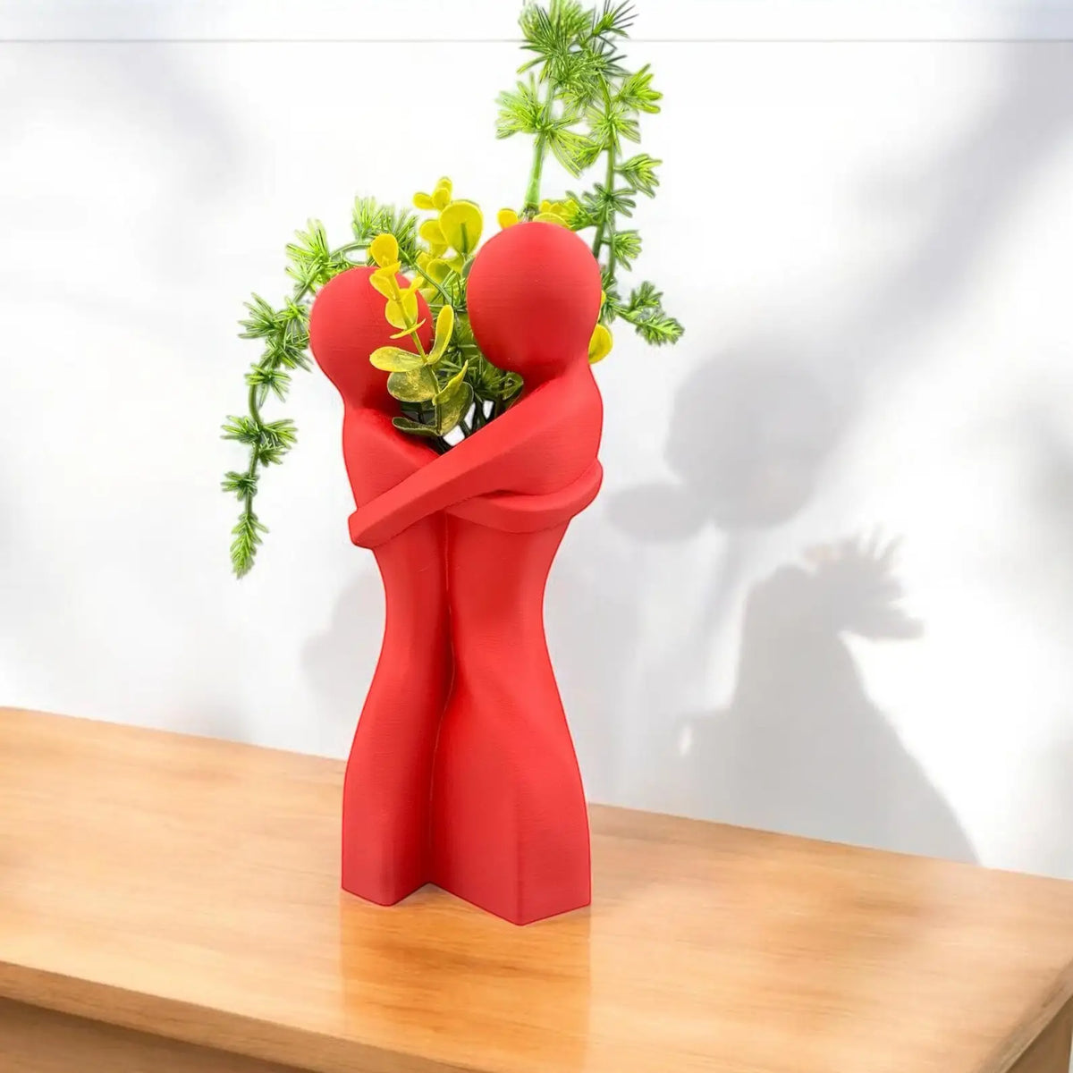 Two ceramic heart vases in white and red arranged on minimalist white marble surface