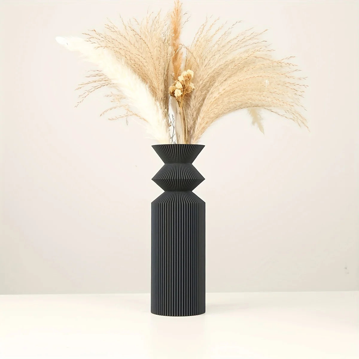 Large Nordic matte black vase holding eucalyptus branch on console
