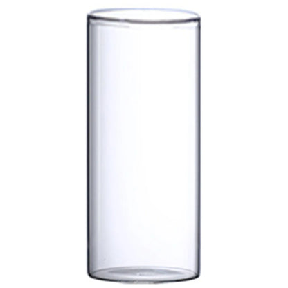 Modern glass cylinder vase with wildflower stems on bathroom shelf beside round mirror