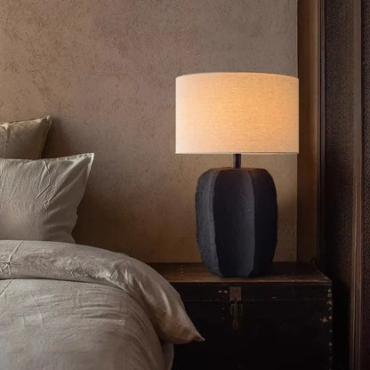 Side view of black clay pottery lamp with linen fabric shade