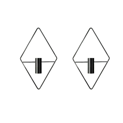 Two black iron geometric wall vases mounted at different heights with dried botanical stems