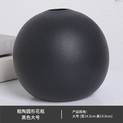 Black ball ceramic vase with single large white peony on console table