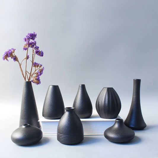 Simple Japanese ceramic small vase in matte black on wooden desk surface