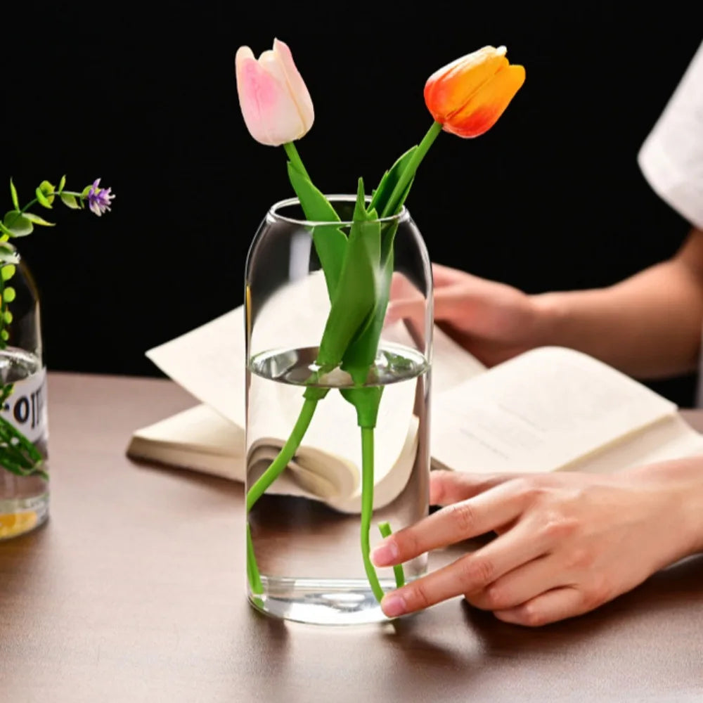 Medium simple glass flower vase with water and green cutting on shelf