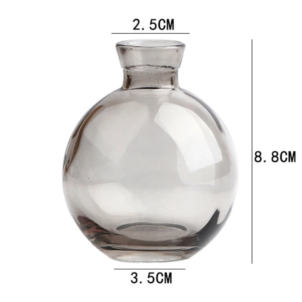 Two mini glass vases in transparent and grey beside each other