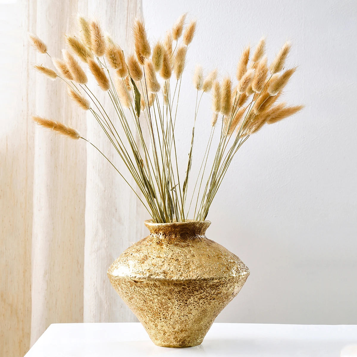 Antique gold wide earthenware jar vase with dried pampas stems on a mantelpiece