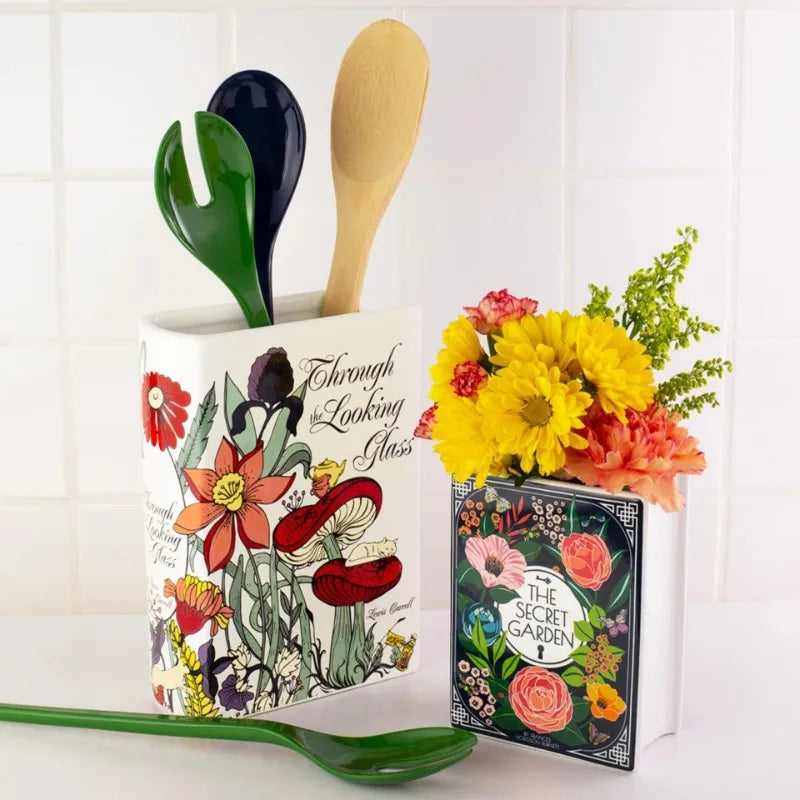 Large ceramic book-shaped vase holding dried lavender on a bookshelf