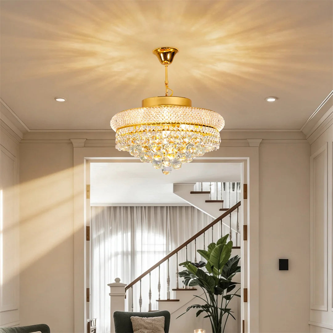 Gold crystal chandelier lit in warm 2700K light over a long table