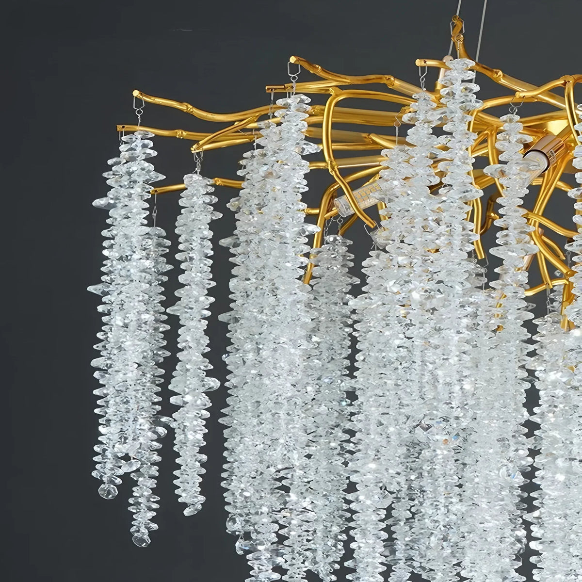 Gold branch chandelier shown in warm light on a cord pendant mounting
