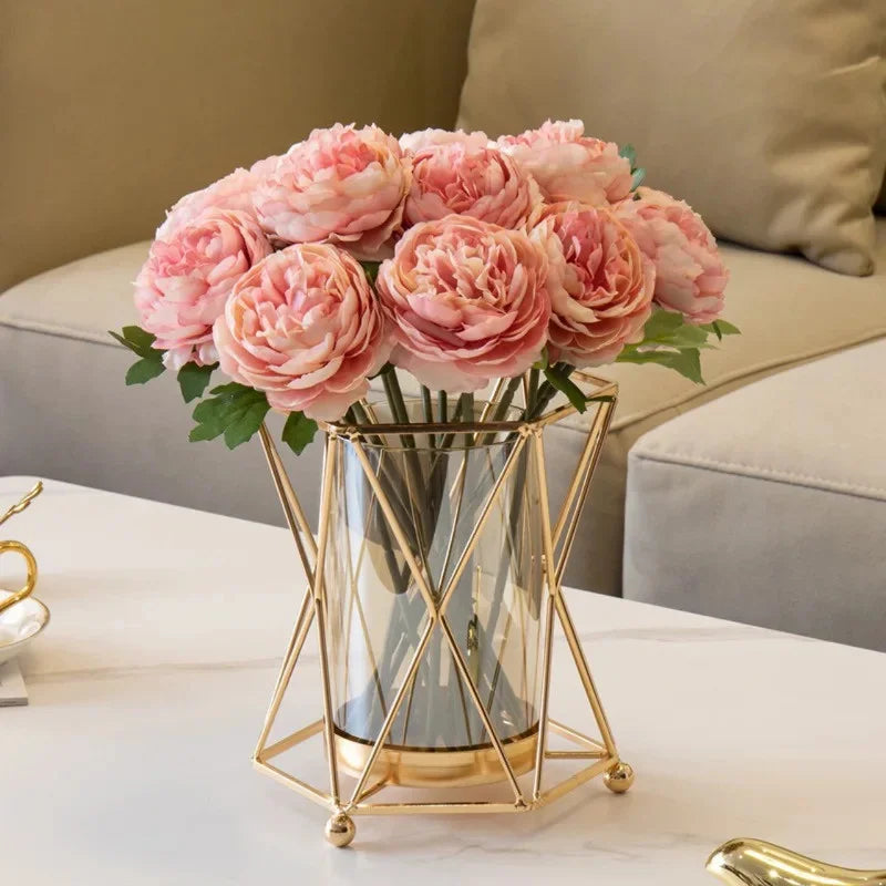 Gold iron geometric vase with glass vessel holding single stem on dining table