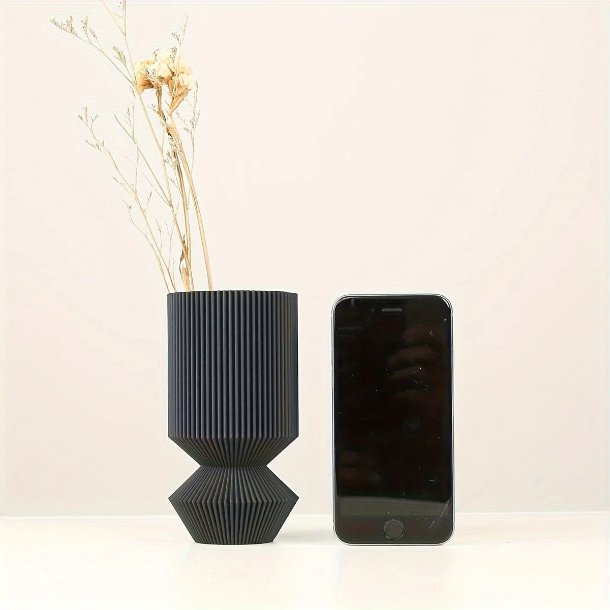Set of three matte black Nordic vases in staggered heights on shelf