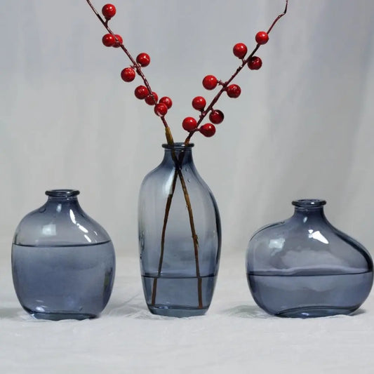 Green-tinted gradient irregular glass mini bud vase holding single flower stem on desk