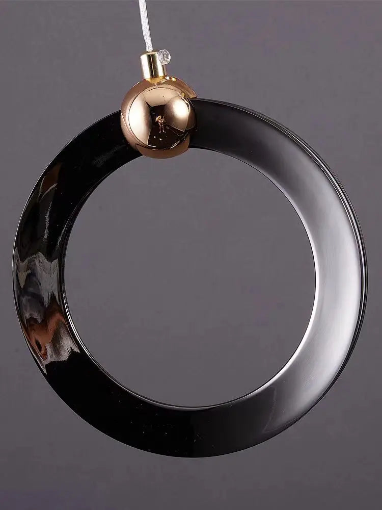 Staircase chandelier lit in warm light down a vertical run of rings