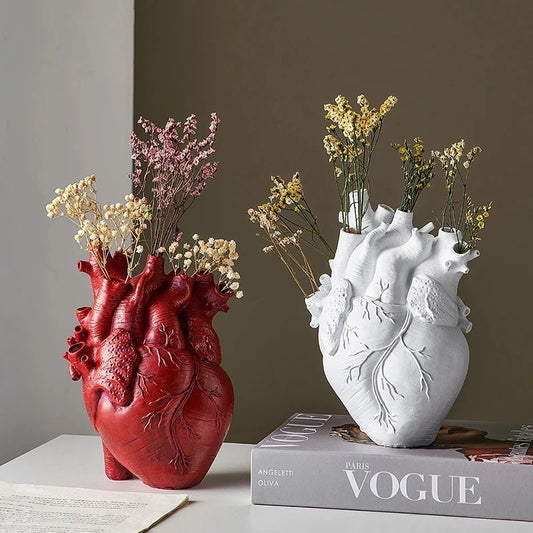 Heart-shaped white resin vase with flower arrangement on desk
