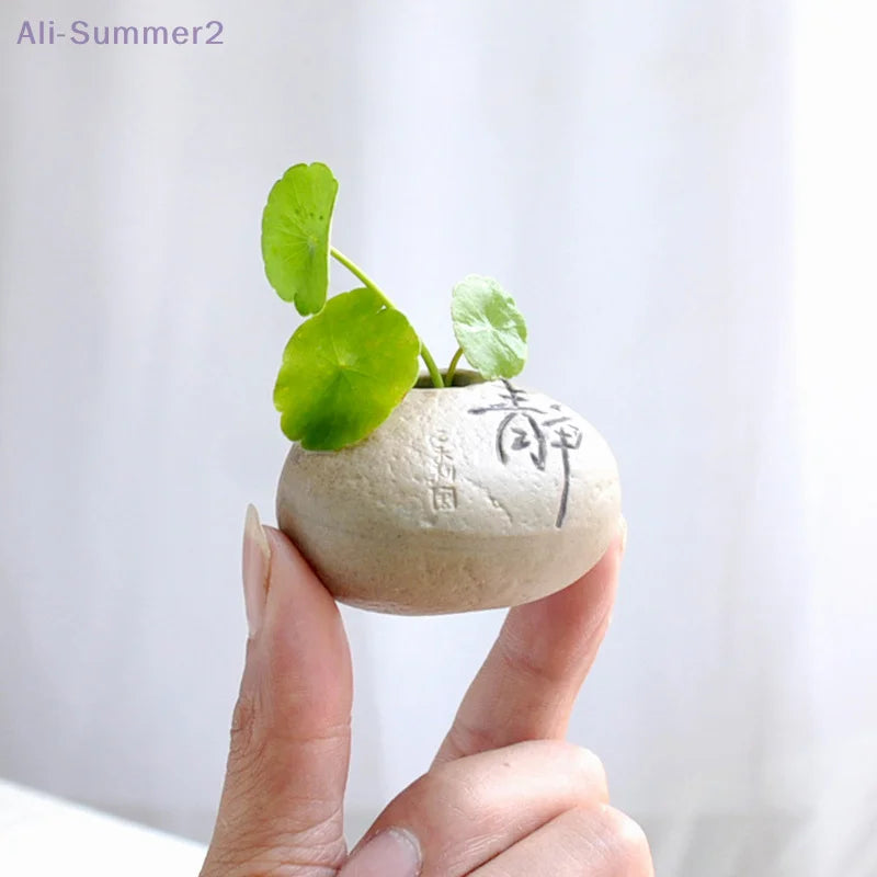 Multiple Zen stone mini ceramic vases in earth tones arranged on white linen surface