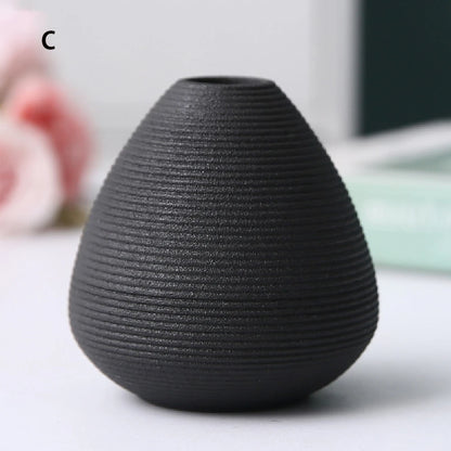 Black ceramic vases B C and D flat lay on natural linen textured background